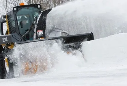 High-flow snow blower attachment on a skid steer throwing snow